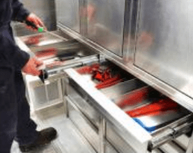 Person organizing tools in a metal workshop drawer.